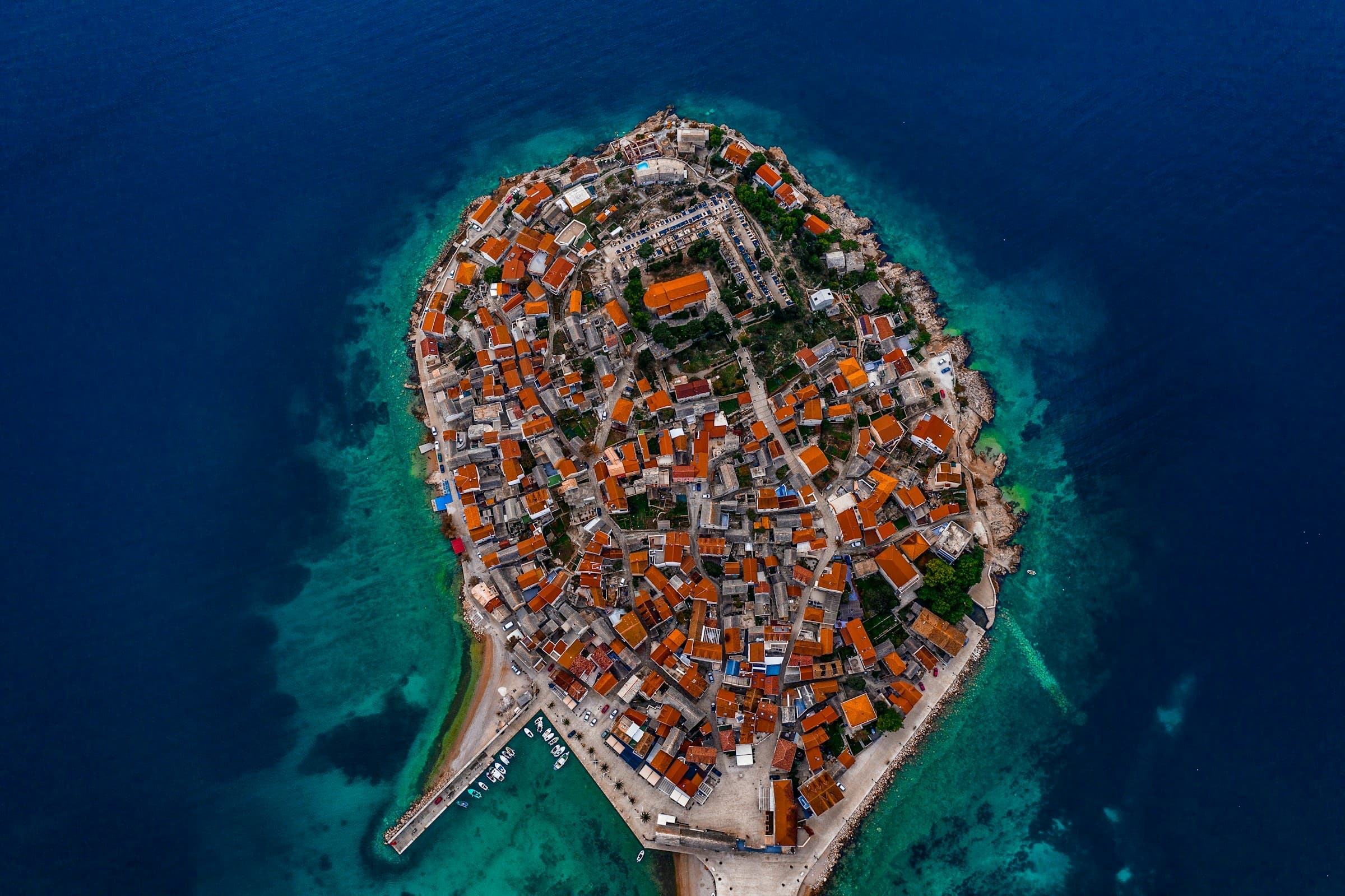 Primošten from above: a stone town on a small peninsula, surrounded by deep blue sea