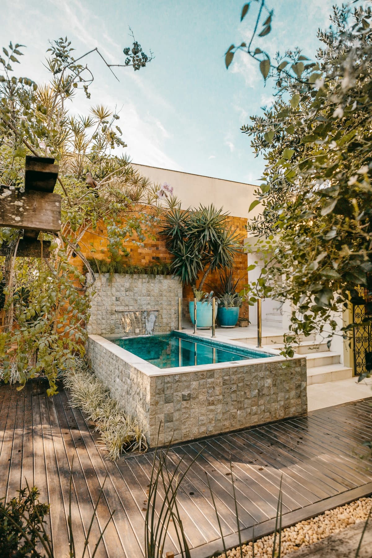 A small pool framed by a stone wall and greenery