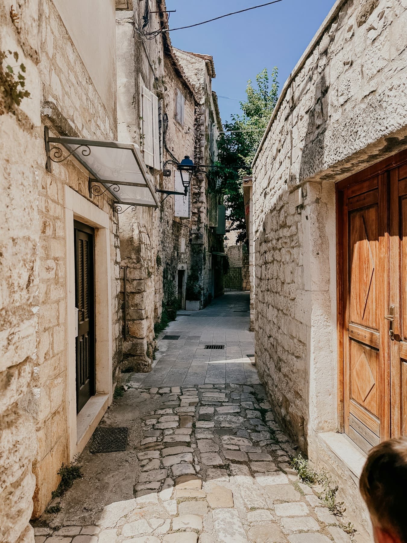 A narrow stone street in Trogir with a wooden door
